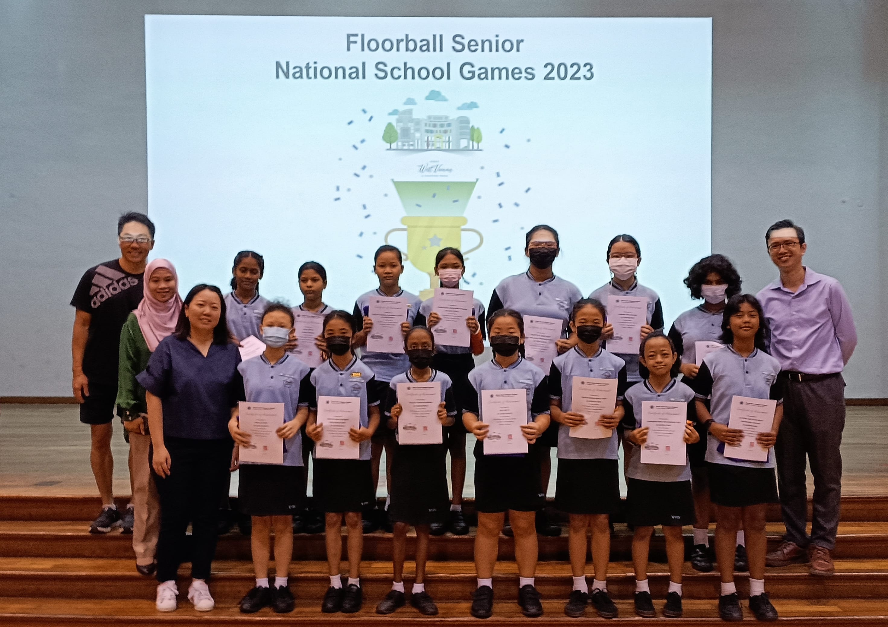 Group of students holding certificates in front of a Floorball Senior National School Games 2023 screen.